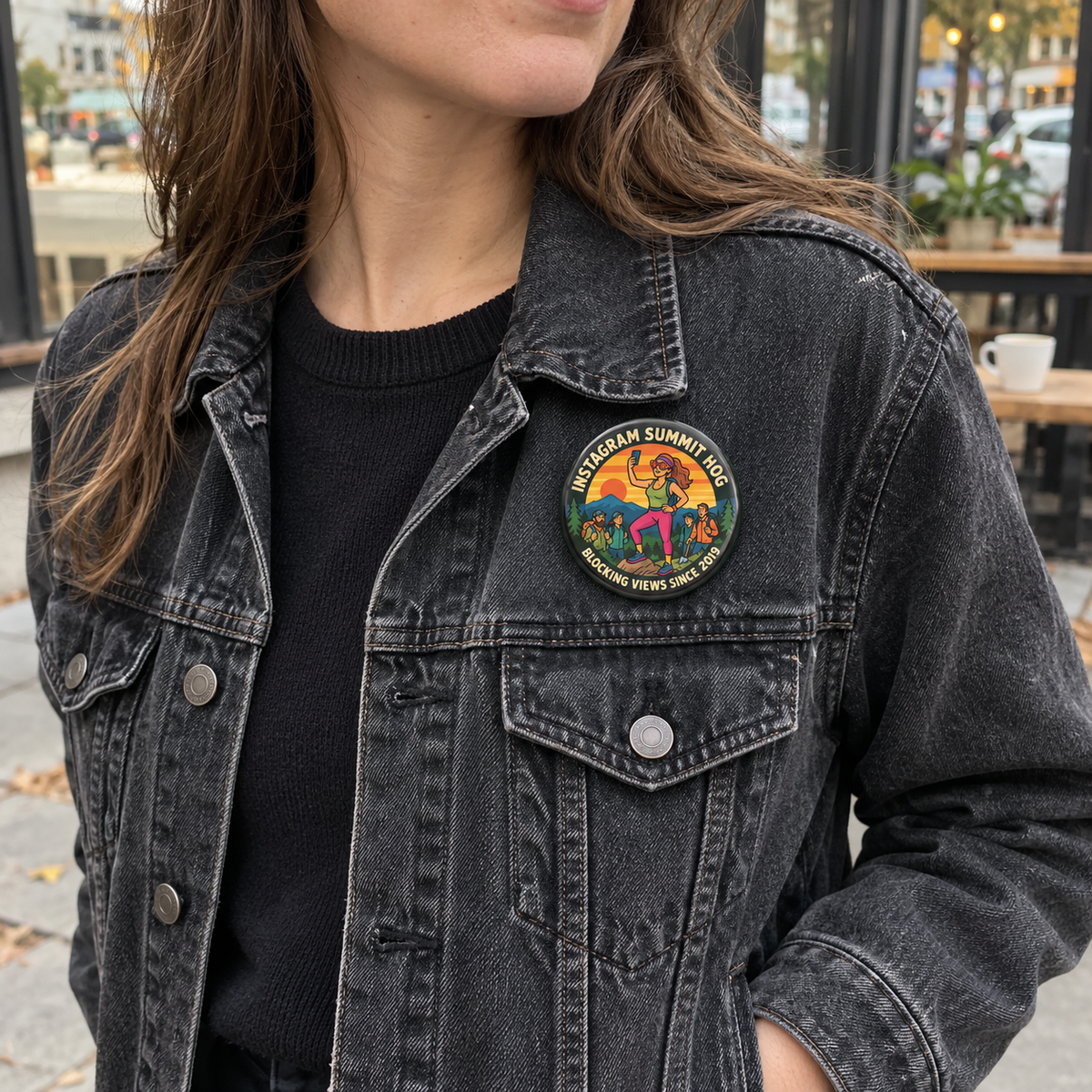 A person wearing a dark washed denim jacket over a black top, with a colorful circular embroidered patch on the left chest. The patch reads 'SUMMIT HOG' and includes a multicolor illustration with the words 'BLOCKING VIEWS SINCE 2019'.