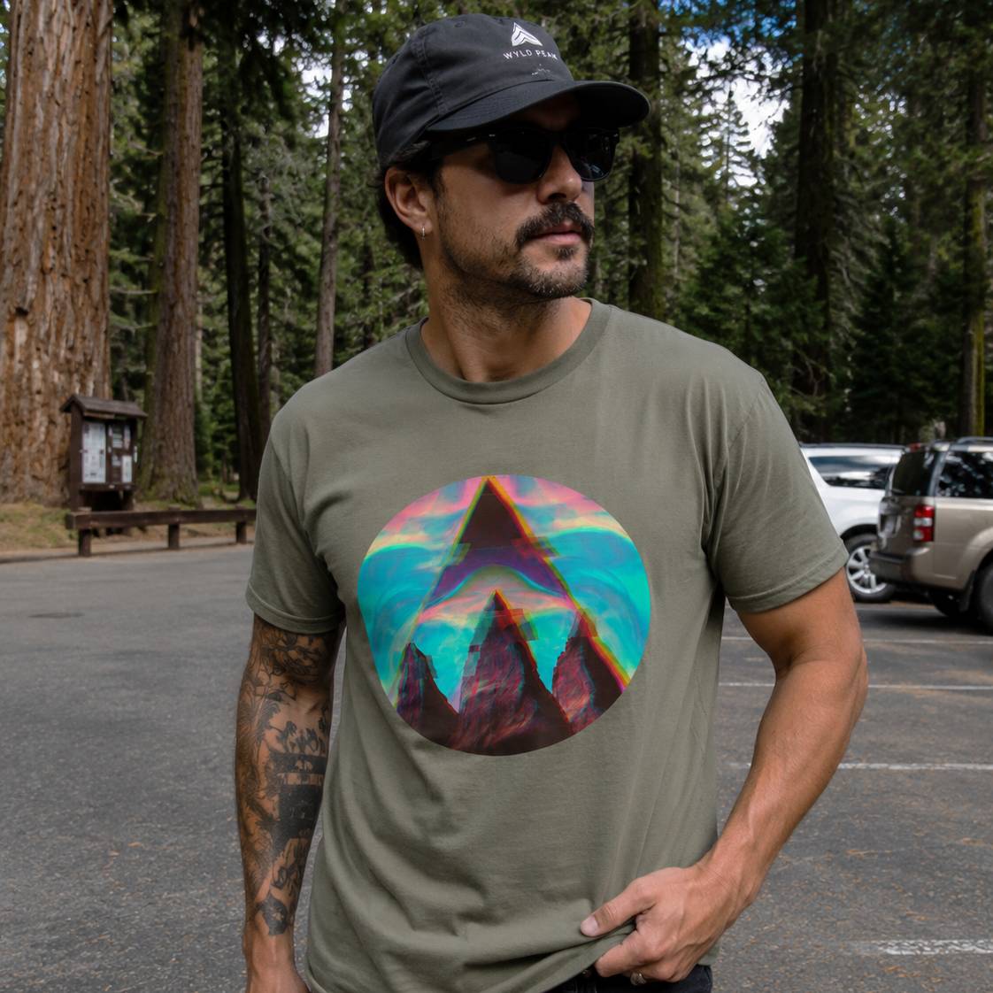 Man wearing a t-shirt with a colorful mountain design in a forest setting