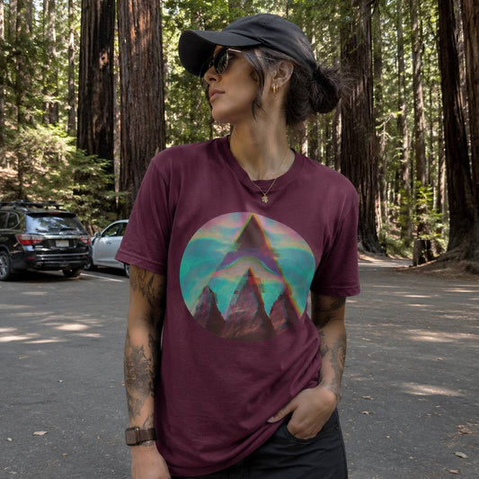 Person wearing a maroon t-shirt with a mountain graphic in a forest setting