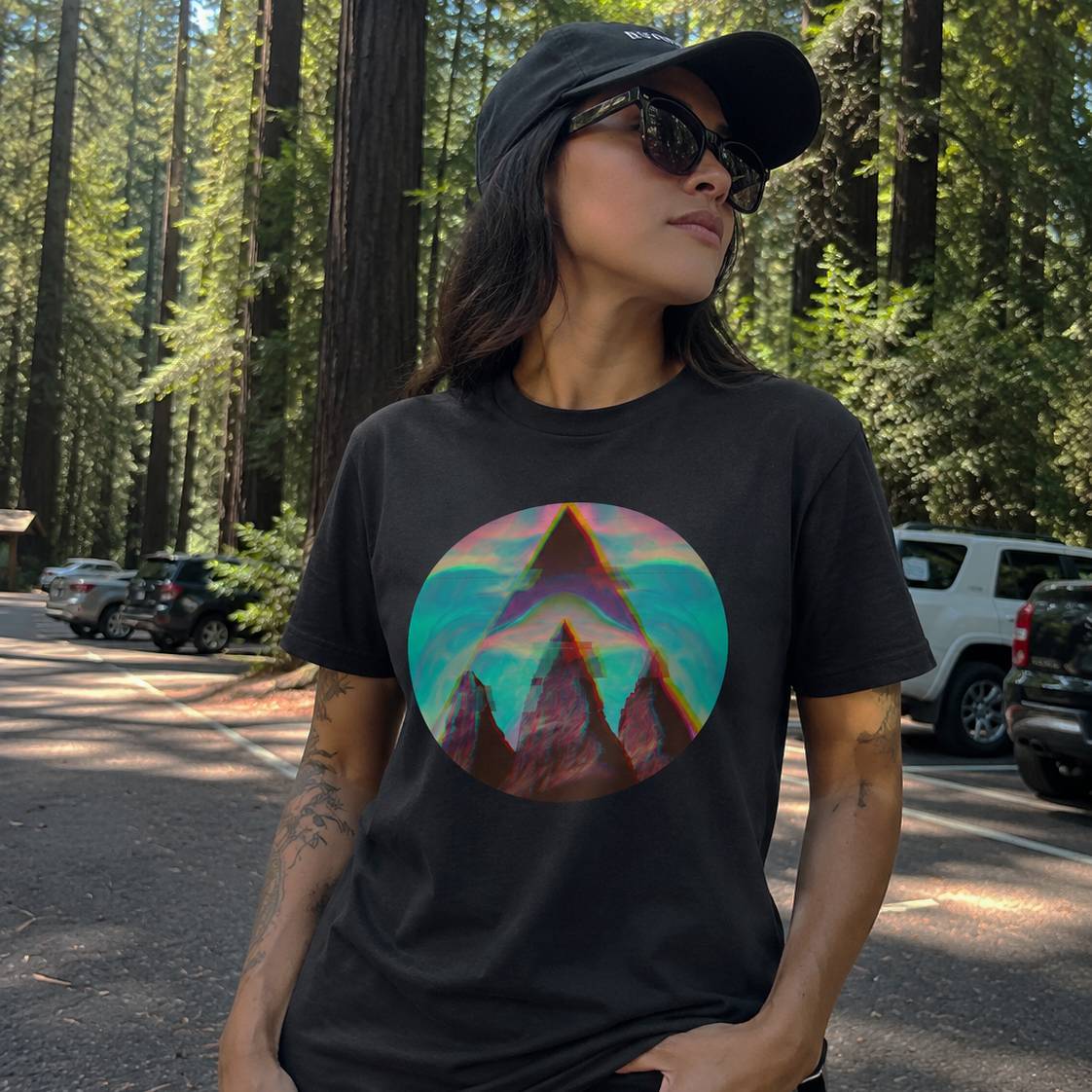Person wearing a black t-shirt with a colorful mountain graphic in a forest setting