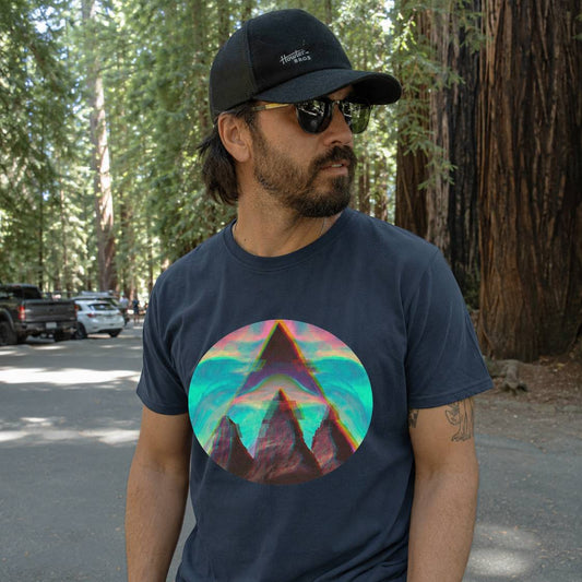 Man wearing a navy t-shirt with a colorful mountain graphic in a forest setting