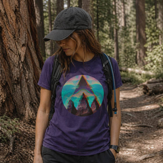 Person wearing a purple t-shirt with a colorful triangle design in a forest setting