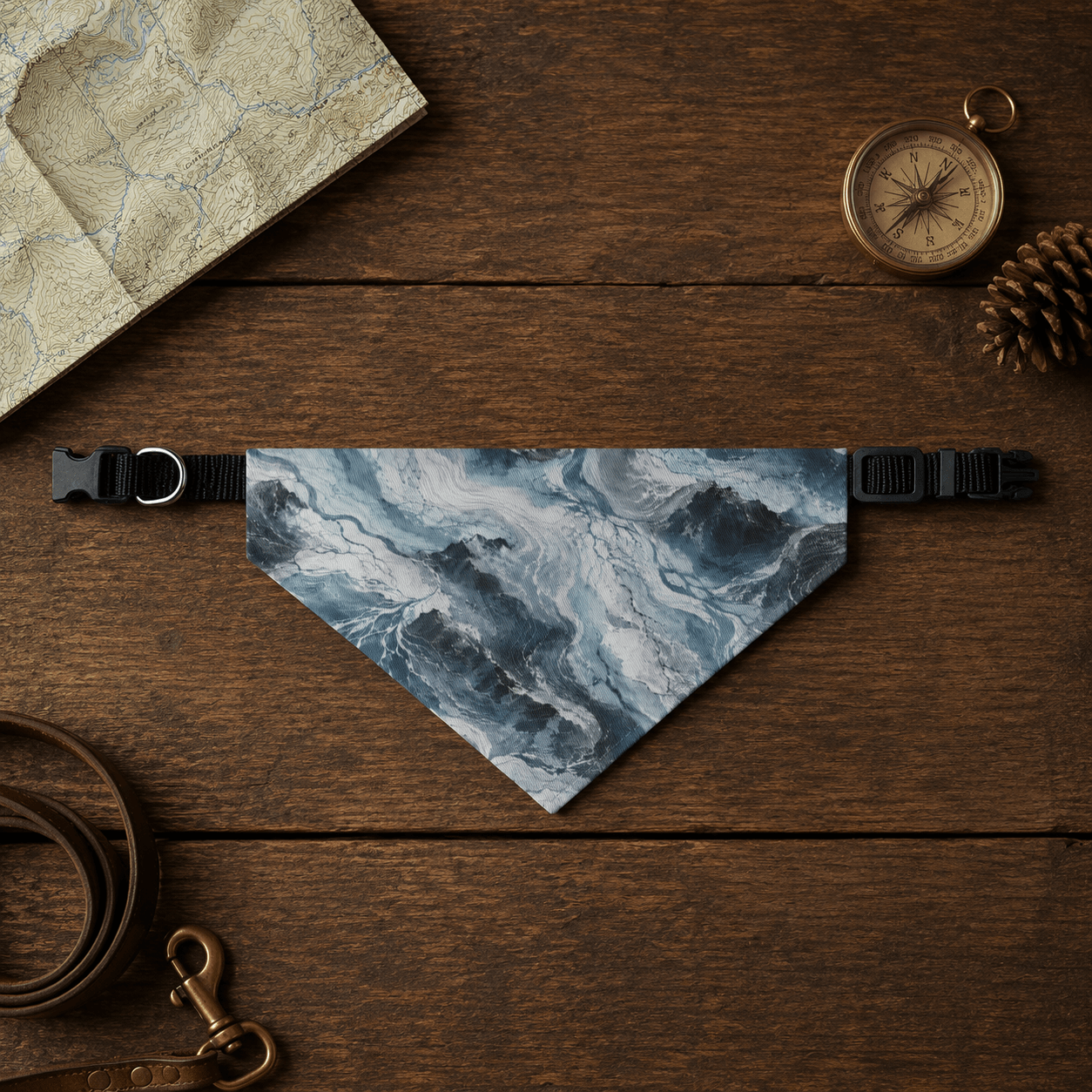 Glacier-patterned dog bandana on a wooden surface with a leash, compass, and pine cone.