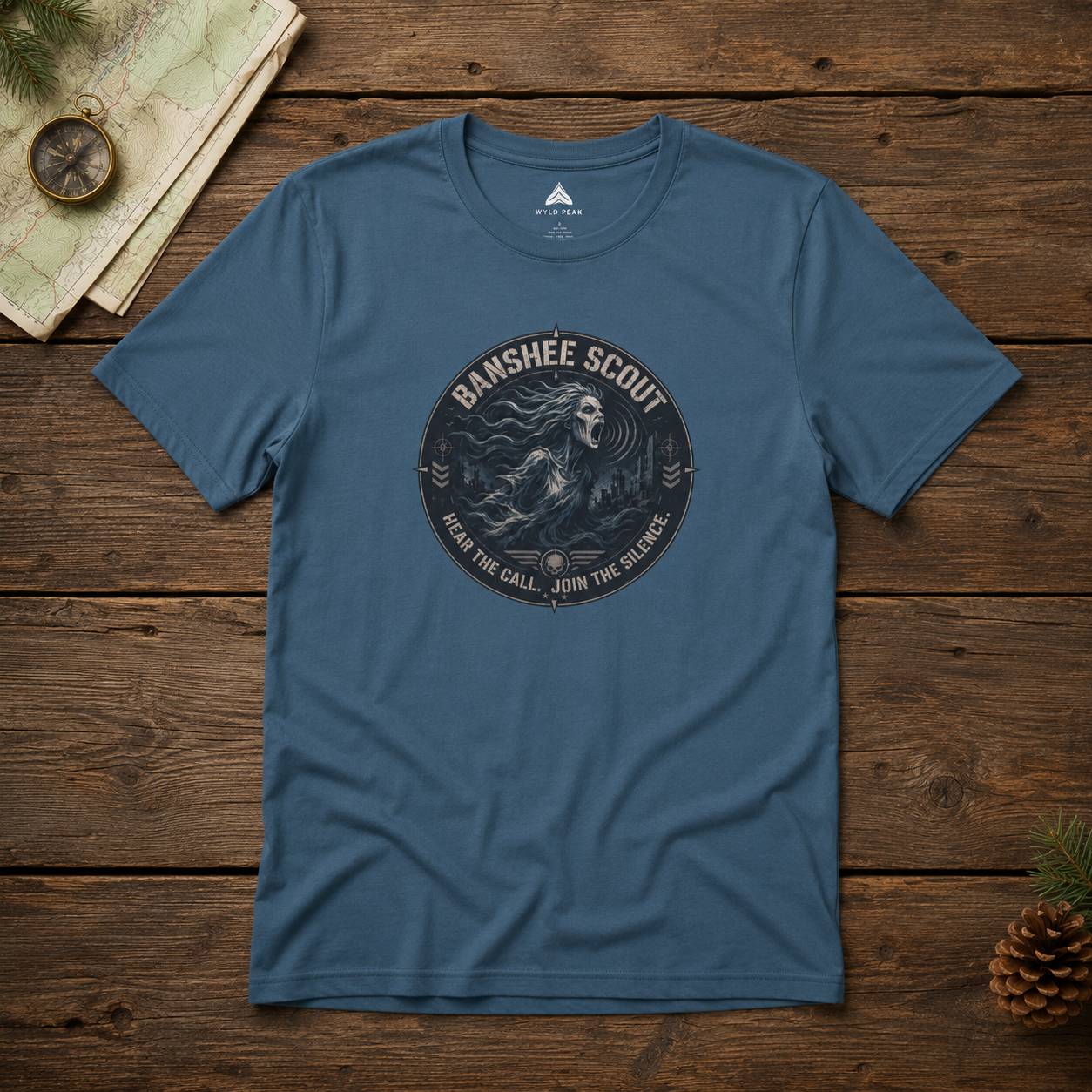 Blue t-shirt with 'Banshee Scout' graphic on a wooden surface