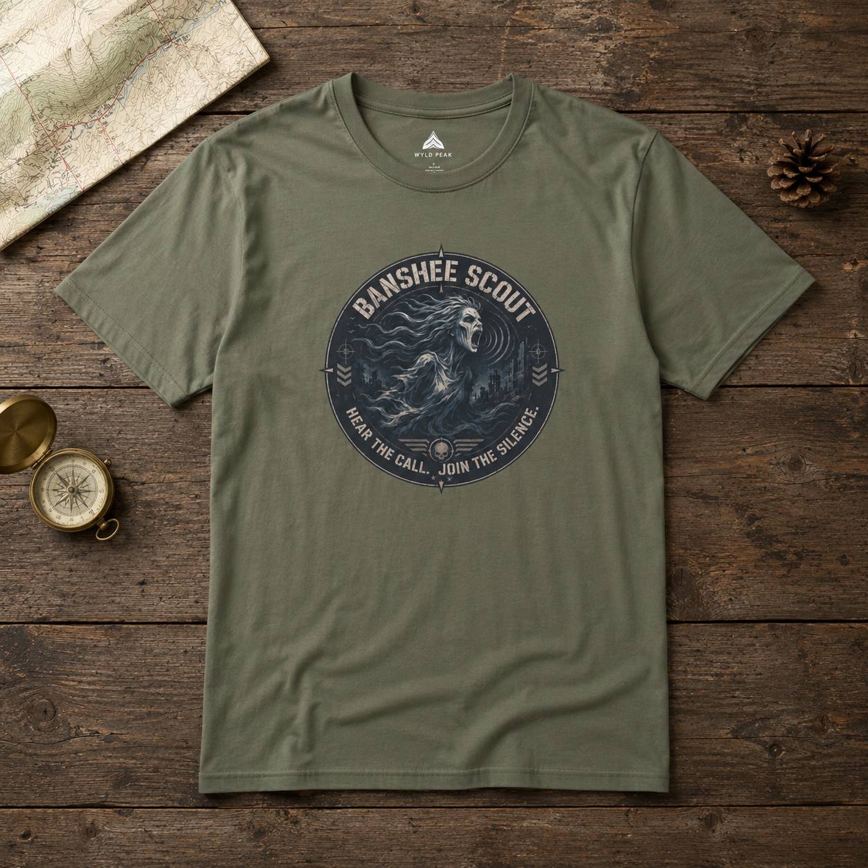 Green t-shirt with 'Banshee Scout' graphic on a wooden surface with map and compass.