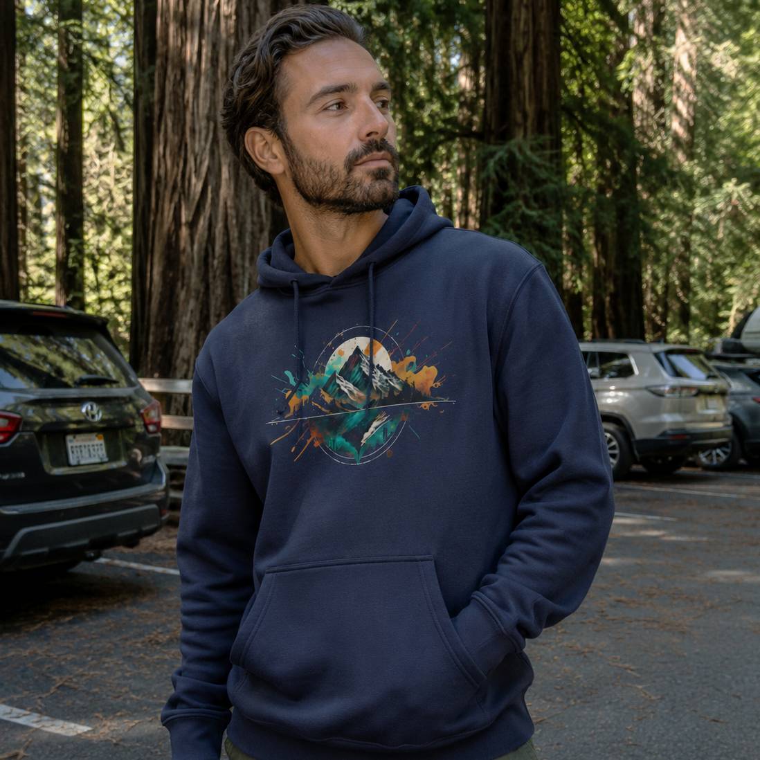 Man wearing a navy blue hoodie with a mountain design in a forest setting