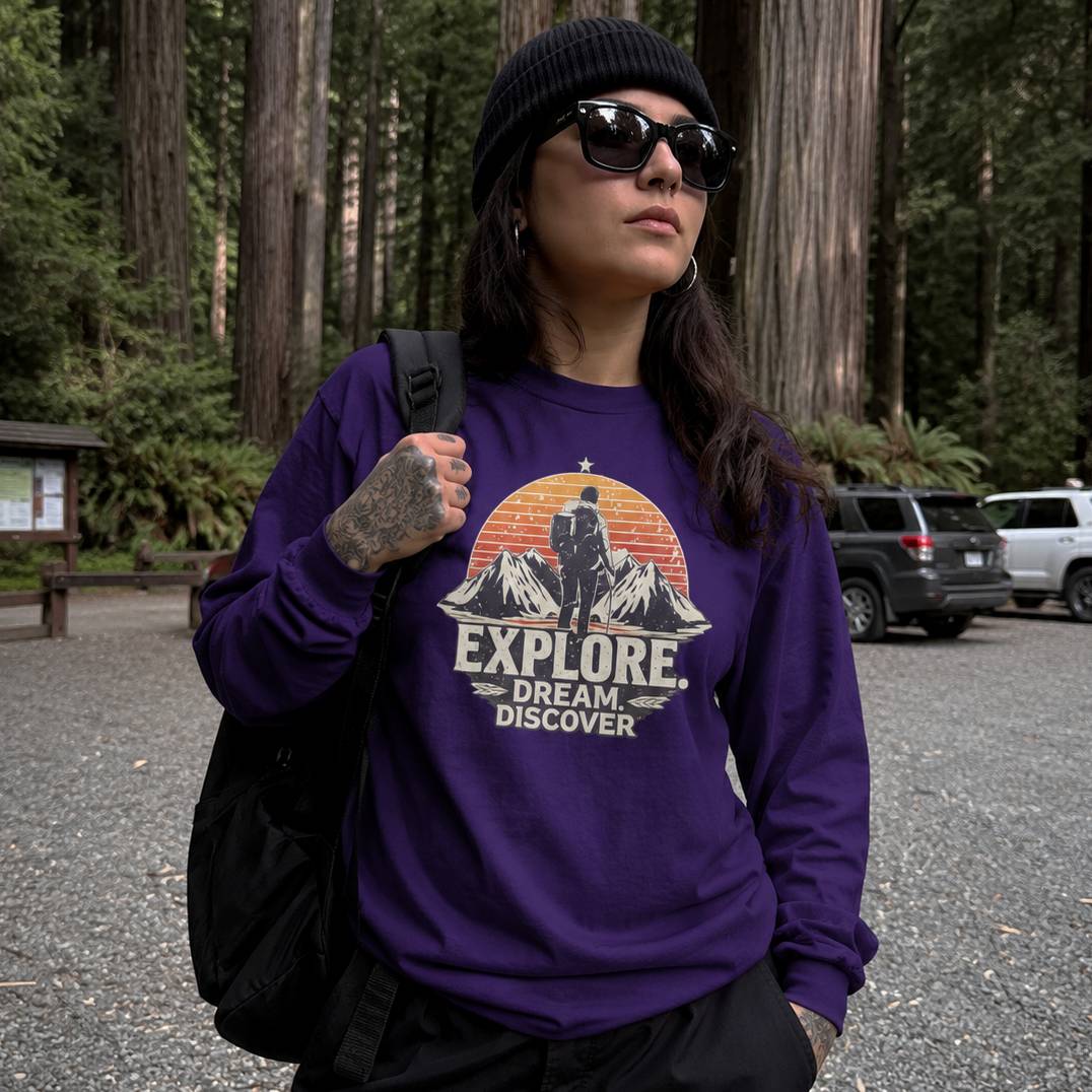 Person wearing a purple sweatshirt with 'Explore Dream Discover' text in a forest setting