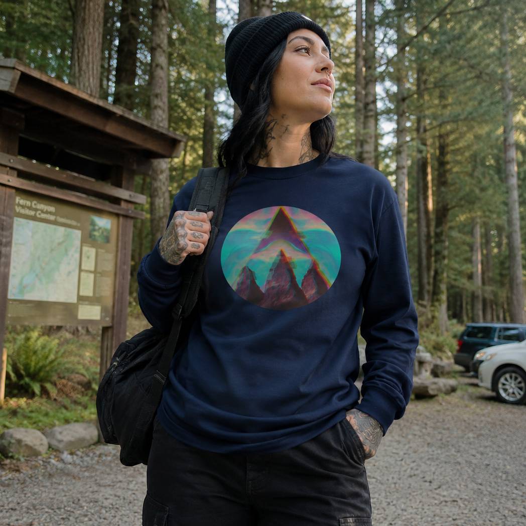 Person wearing a navy sweatshirt with a colorful mountain design in a forest setting.