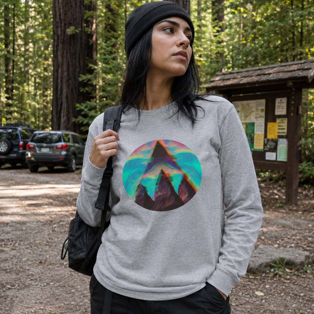 Woman wearing a gray sweatshirt with a colorful mountain design in a forest setting