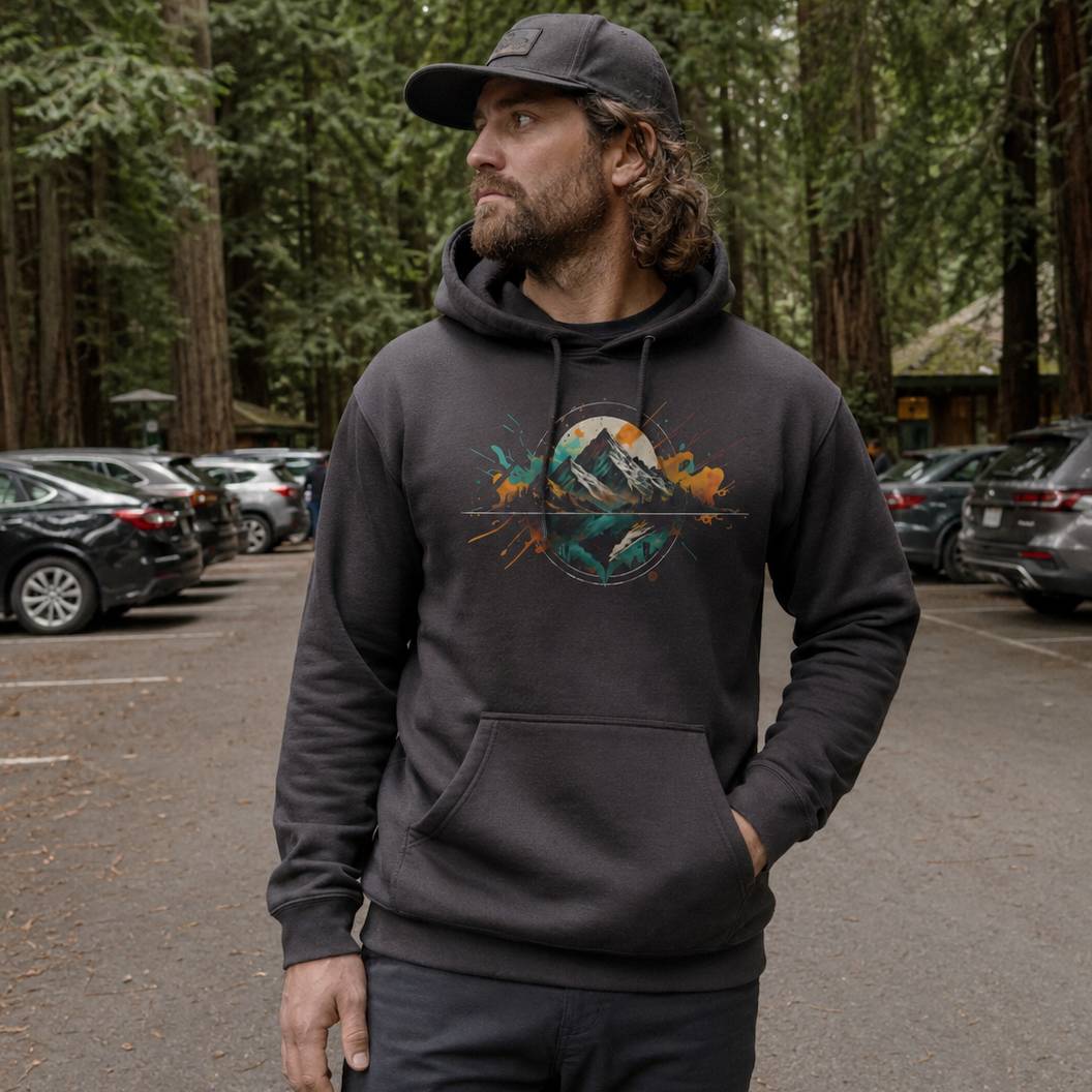 Man wearing a dark hoodie with a nature graphic in a parking lot with trees in the background