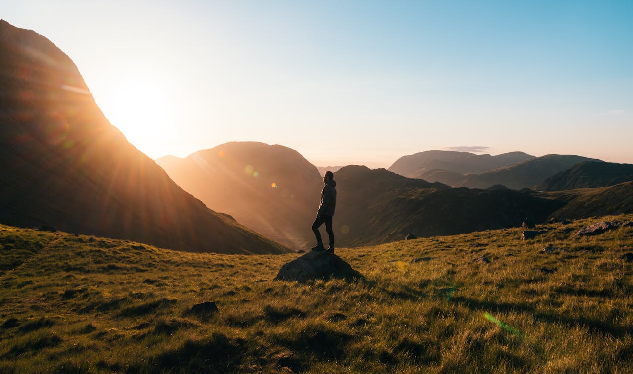 Hiker standing on large rocks overlooking a lush North American valley.