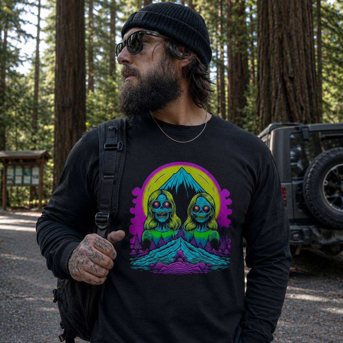 Man wearing a black t-shirt with a colorful graphic design in a forest setting