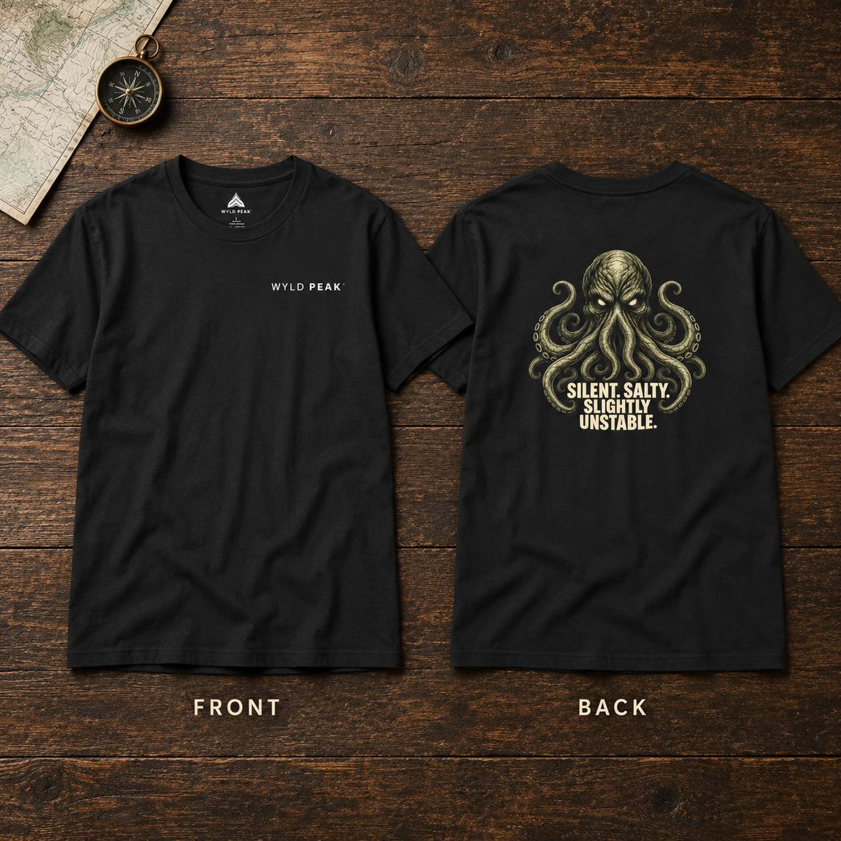 Two black short-sleeve T-shirts shown front and back on a dark wood background. The front has small white 'WYLD PEAK' text on the left chest, and the back has a large gold-toned octopus graphic with the phrase 'SILENT, SALTY, SLIGHTLY UNSTABLE.