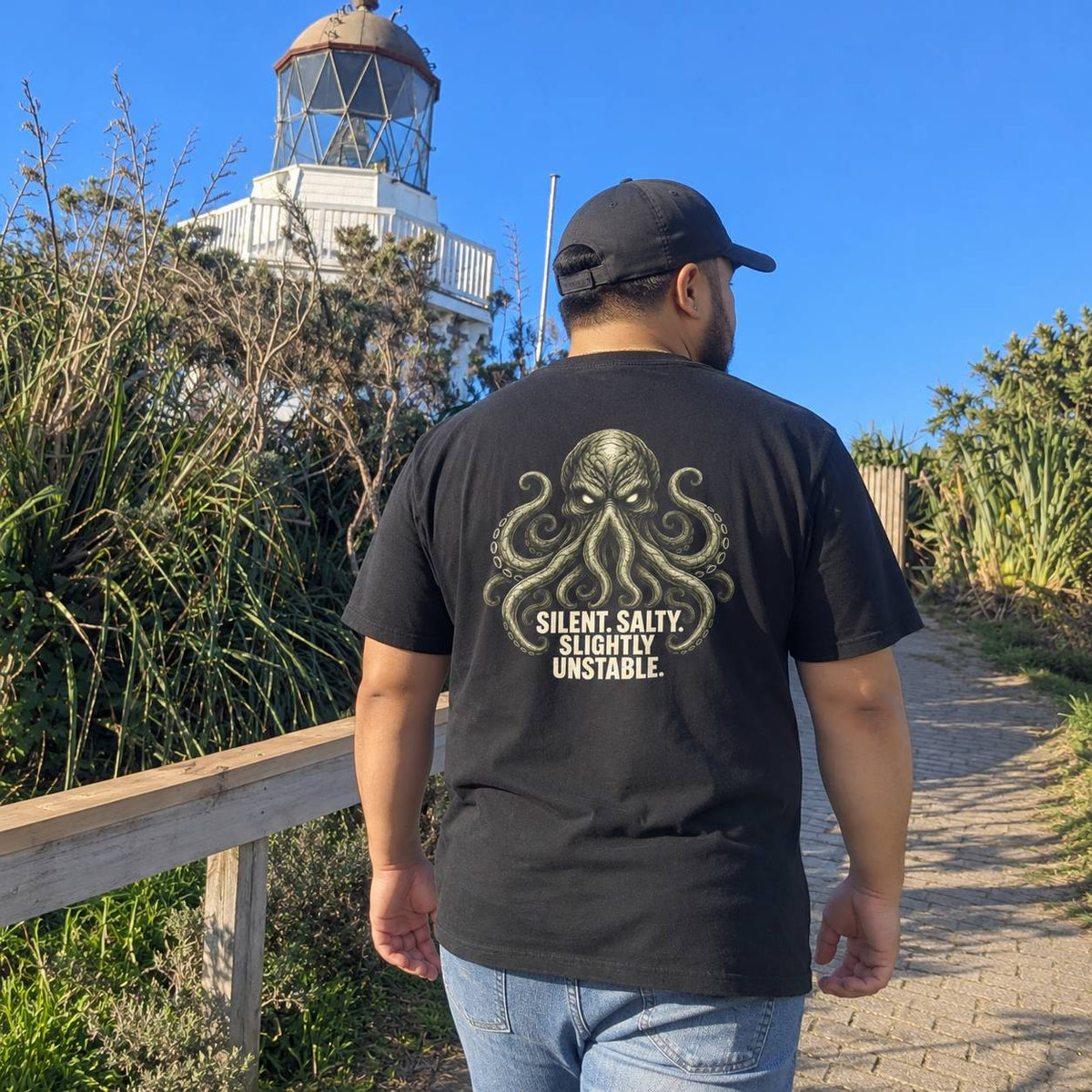 A man viewed from behind wearing a black t-shirt with a large graphic of a tentacle creature and the text 'SILENT, SALTY. SLIGHTLY UNSTABLE.