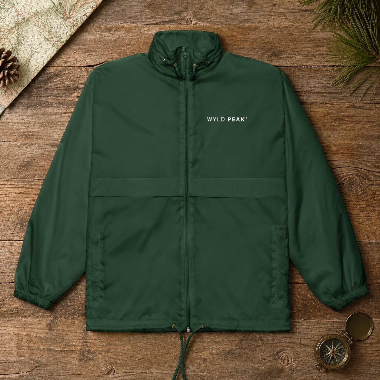 Green jacket with 'WYLD PEAK' logo on a wooden surface with nature-themed items.