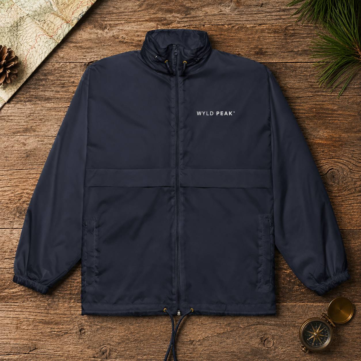 Navy jacket with 'WYLD PEAK' logo on a wooden surface with nature-themed elements.