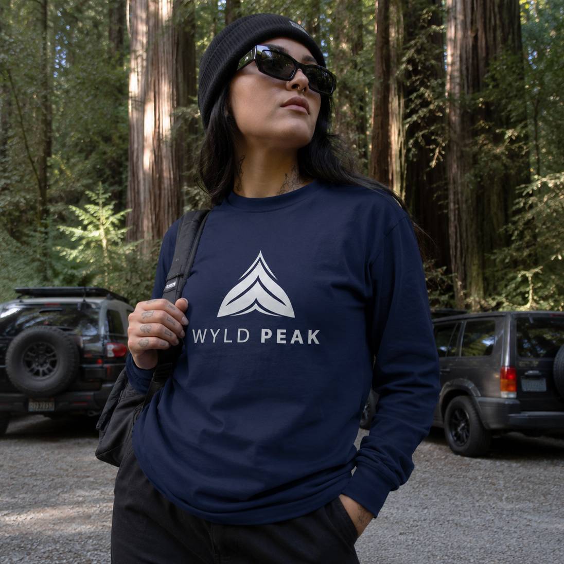 Person wearing a navy blue sweatshirt with 'Wyld Peak' logo in a forest setting