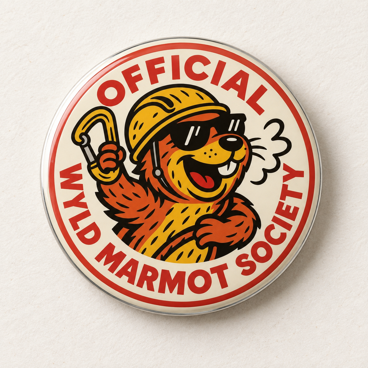 A round pinback button featuring a cartoon marmot wearing a yellow helmet and sunglasses, with the text 'OFFICIAL WYLD MARMOT SOCIETY' in red around the border, shown on a light textured background.
