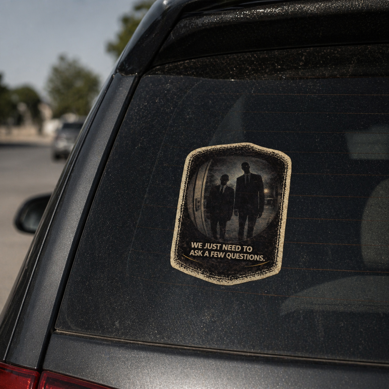 Car window with a decal featuring two people and text on a blurred street background
