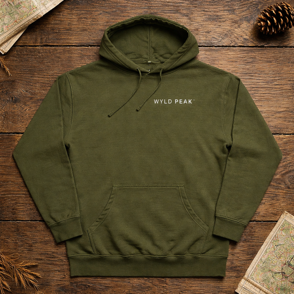 Green hoodie with 'WYLD PEAK' logo on a wooden surface with nature-themed decor.