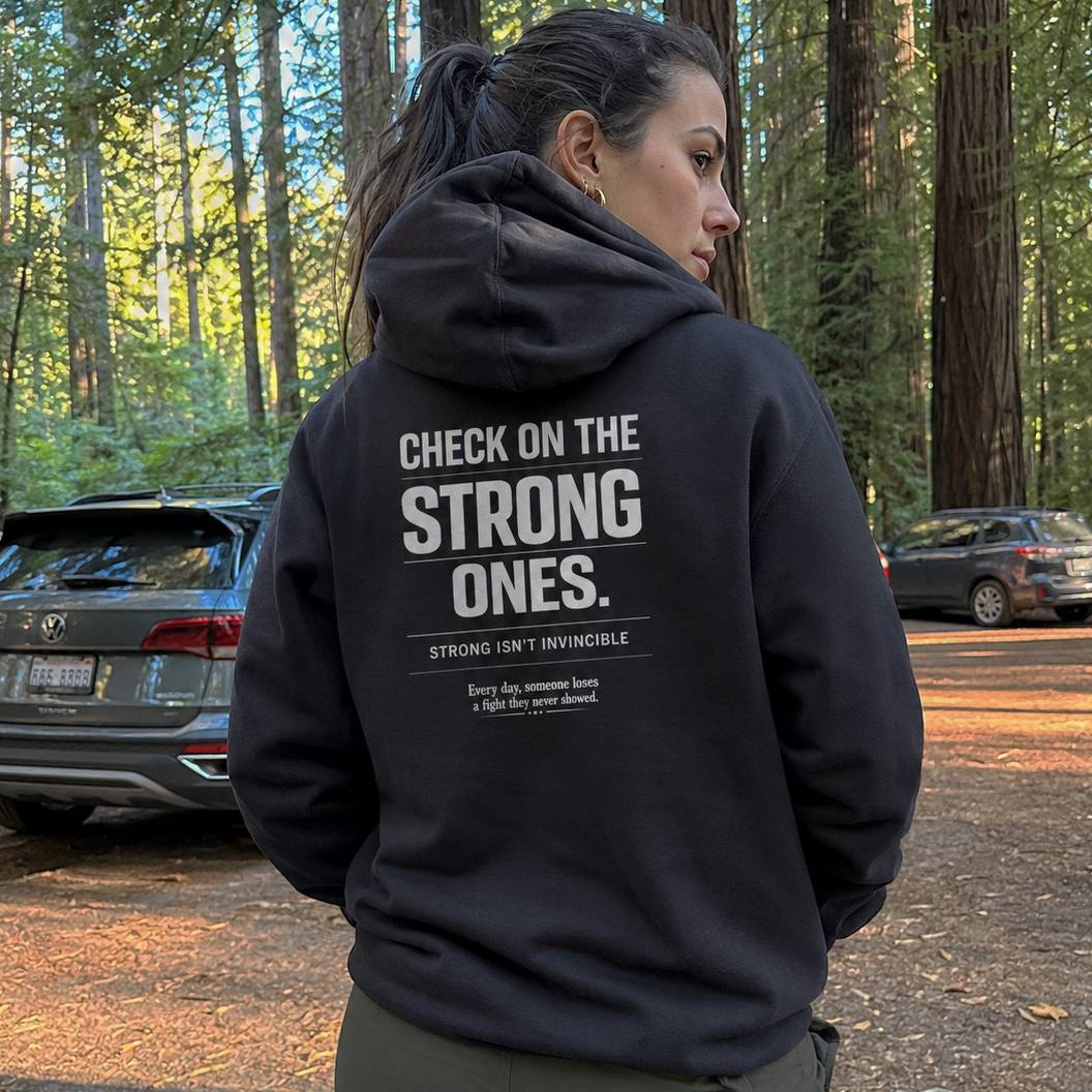 Person wearing a black hoodie with text in a forest setting