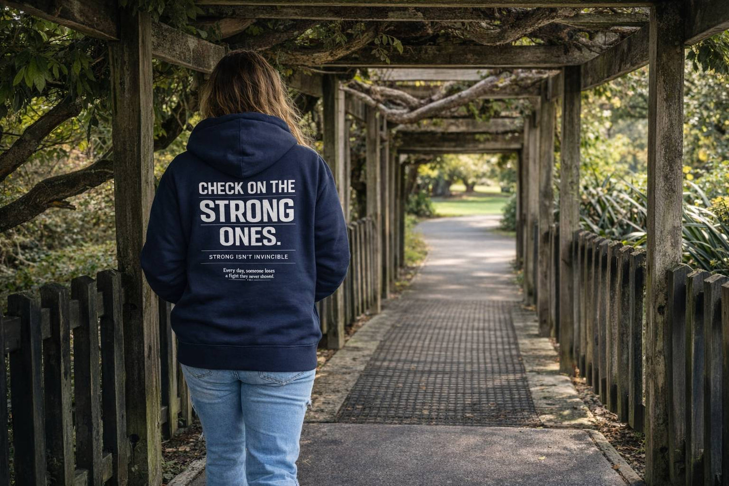 Person wearing a mental health hoodie with text walking through a wooden pathway