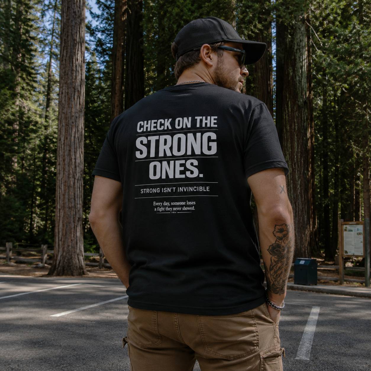 Man wearing a black t-shirt with a motivational quote in a forest setting