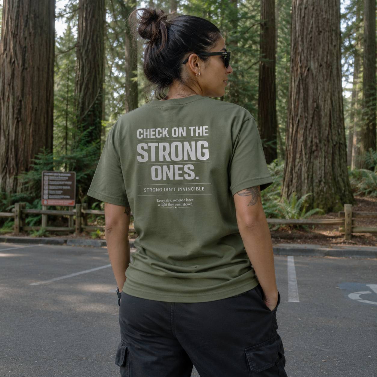 Person wearing a green t-shirt with text in a forest setting