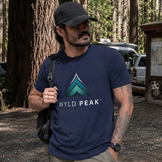 Man wearing a navy blue 'Wyld Peak' t-shirt in a forest setting