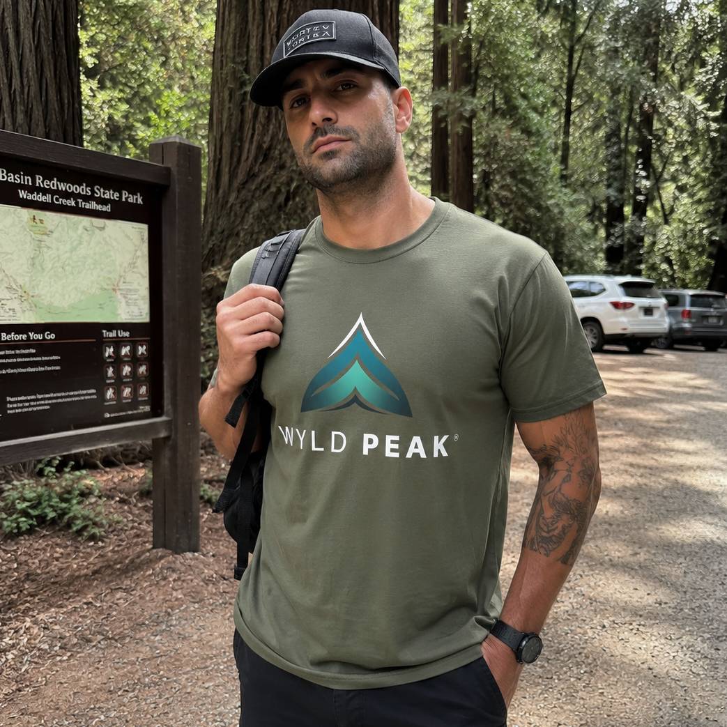 Man wearing a green t-shirt with a logo in a forest setting