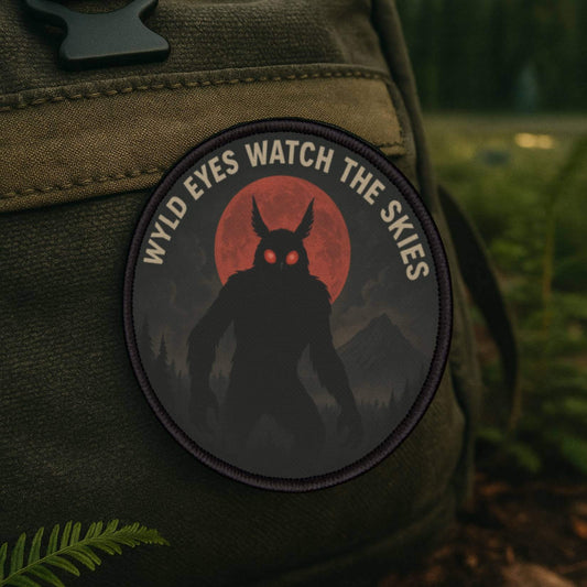 Mothman patch on a backpack in a shadowy American forest, cryptid-themed