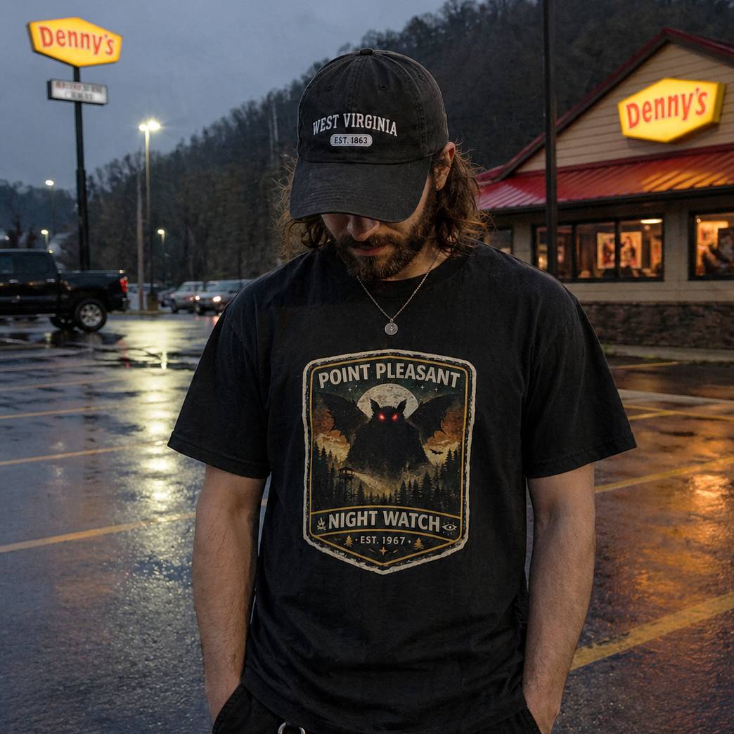 Person wearing a black t-shirt with 'Point Pleasant Night Watch' design and a cap, standing in front of a Denny's restaurant.