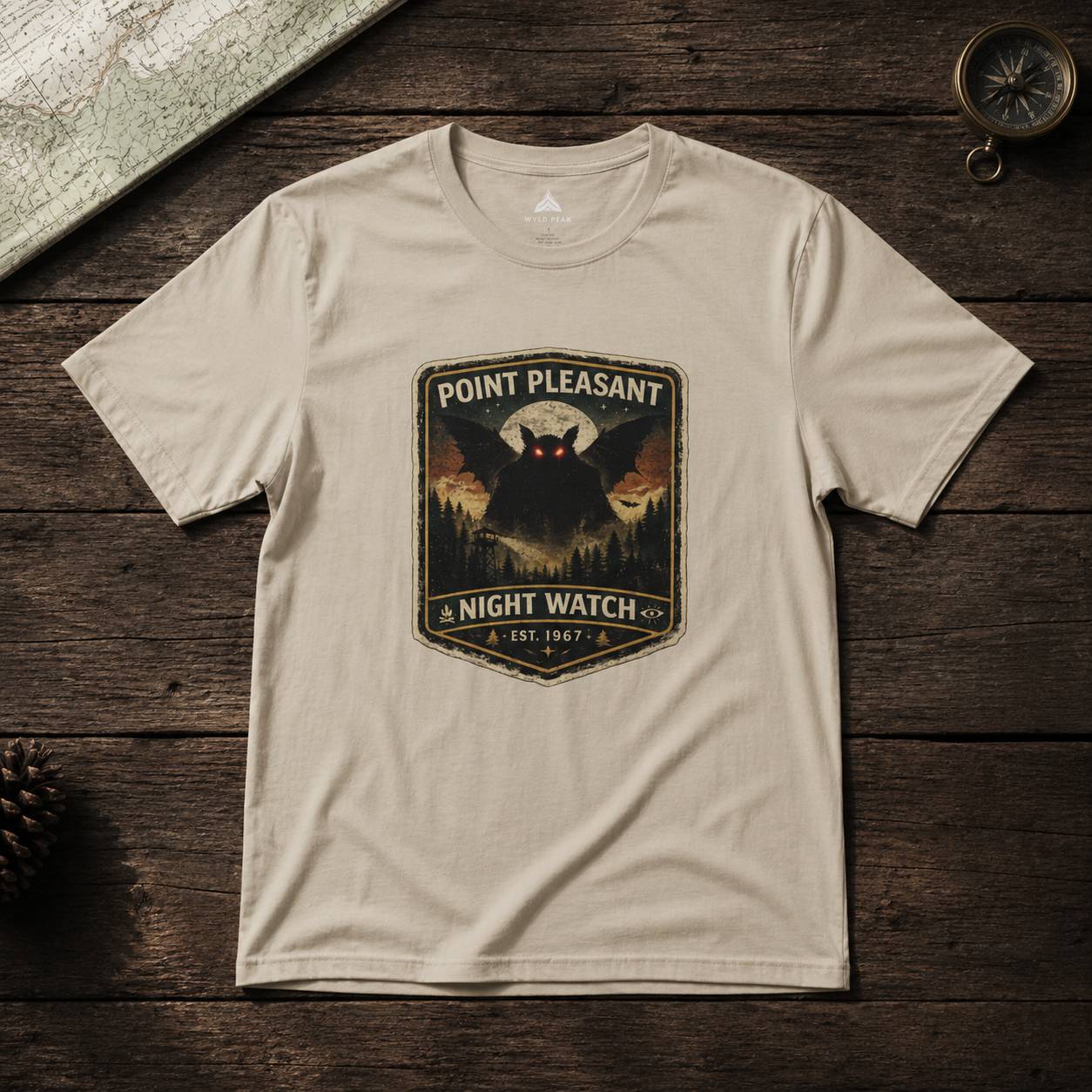 Beige t-shirt with 'Point Pleasant Night Watch' graphic on a wooden surface
