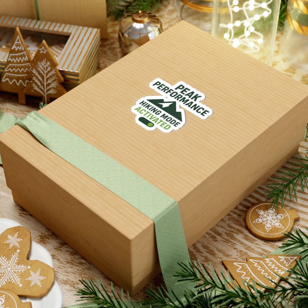 Wooden gift box with green ribbon and 'Peak Performance' sticker on a festive background with cookies and decorations.