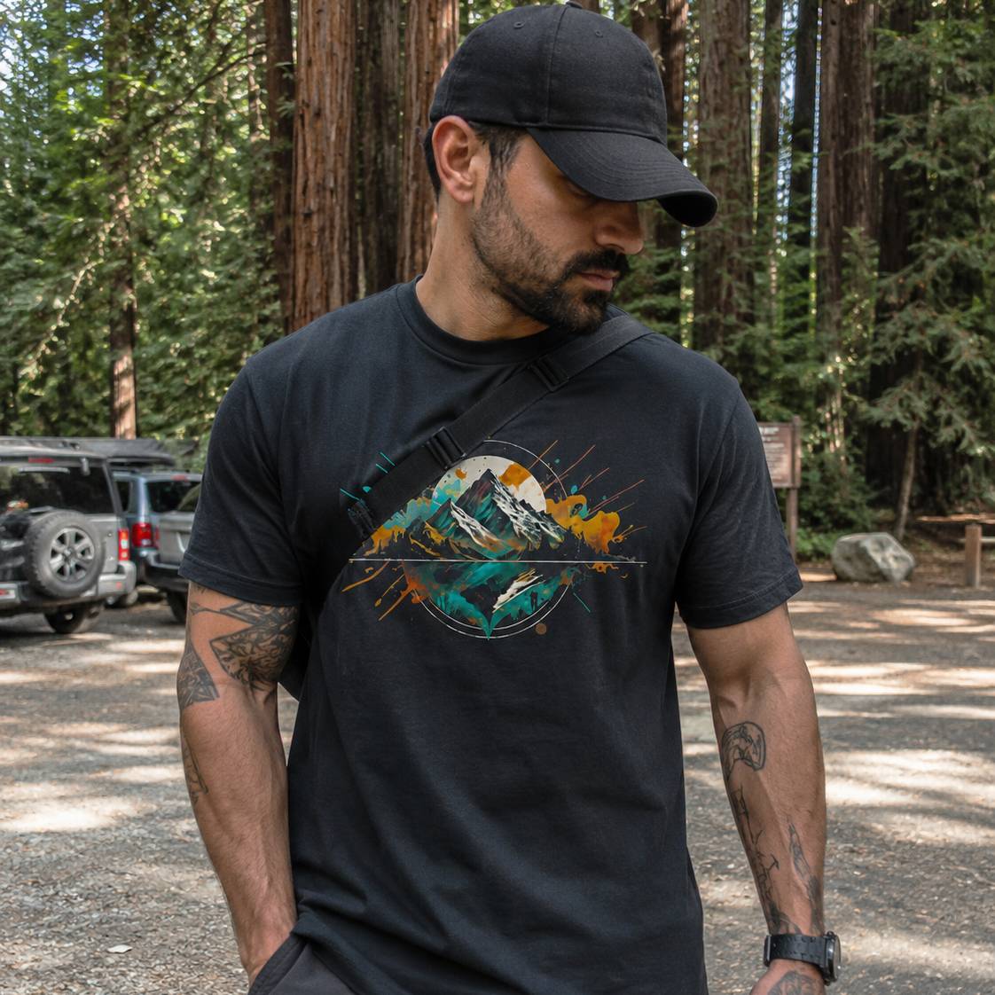 Man wearing a black t-shirt with a mountain graphic in a forest setting