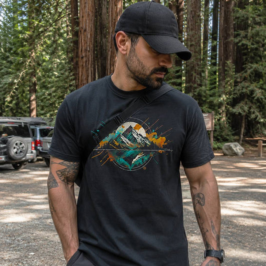 Man wearing a black t-shirt with a mountain graphic in a forest setting