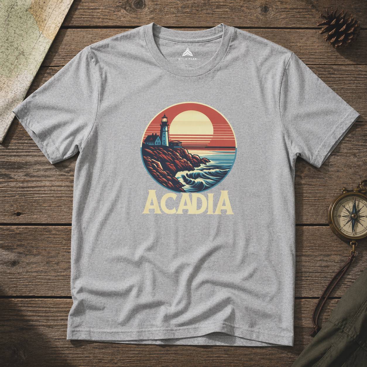 Gray t-shirt with 'Acadia' design featuring a lighthouse and ocean on a wooden surface.