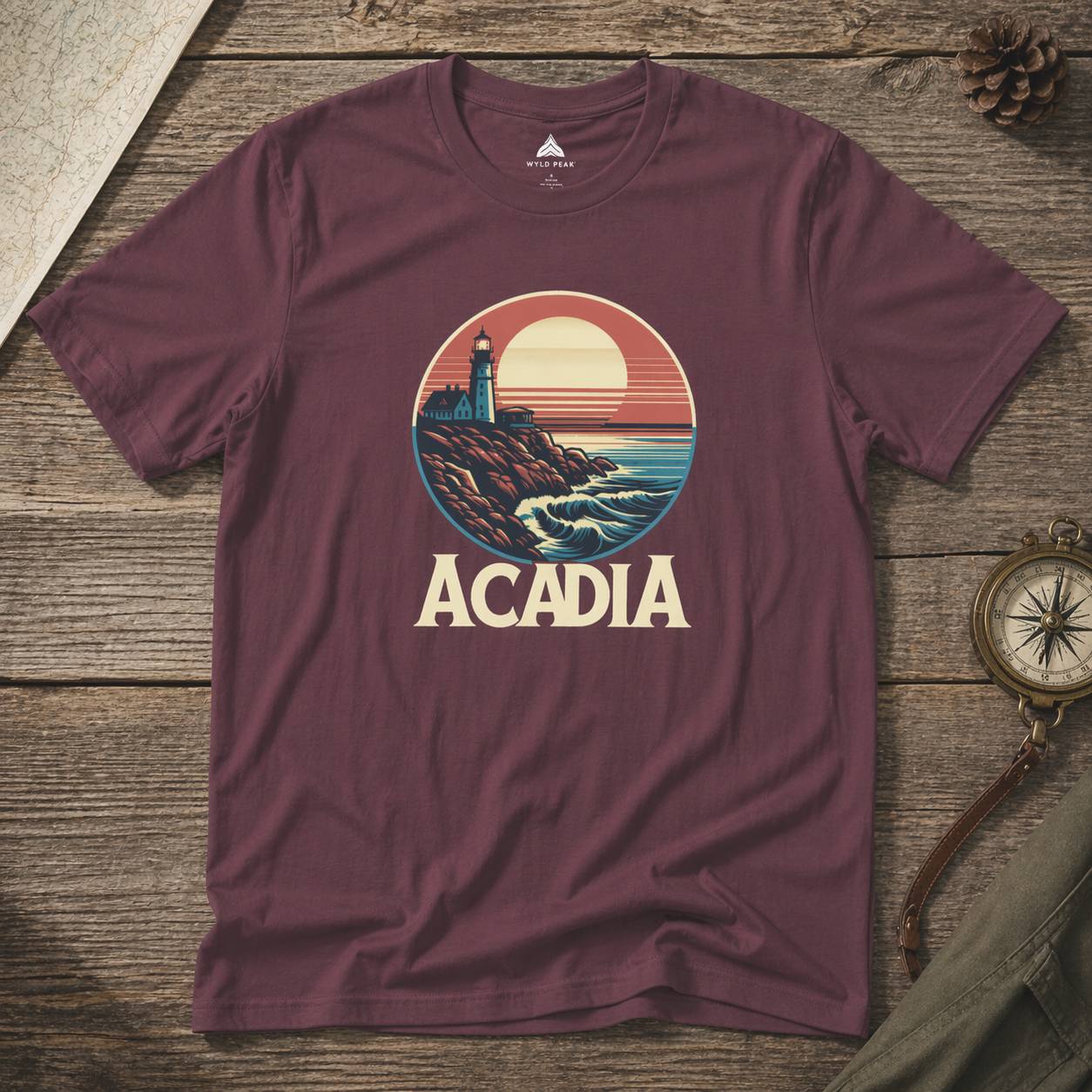 Maroon t-shirt with Acadia national park graphic on a wooden surface