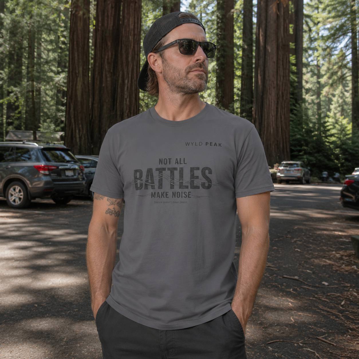 Man wearing a gray t-shirt with text in a forest setting