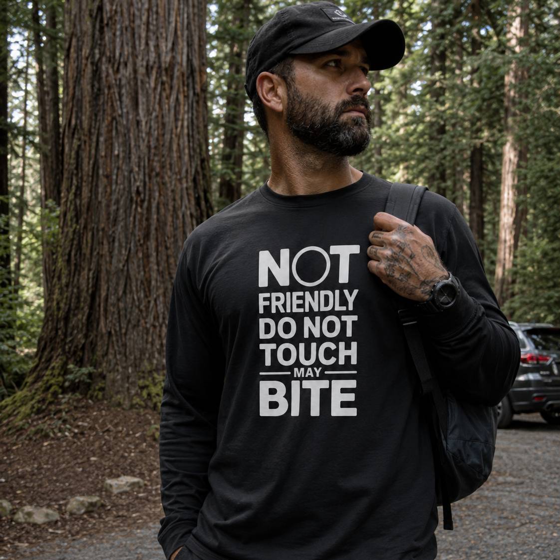 Man wearing a black t-shirt with text in a forest setting