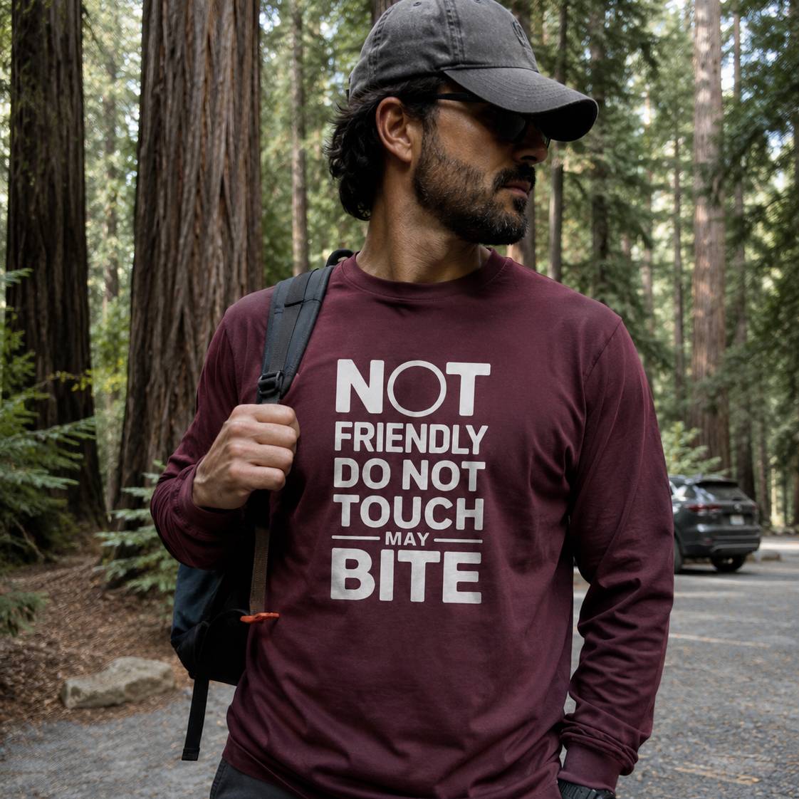 Man wearing a maroon long-sleeve shirt with text in a forest setting