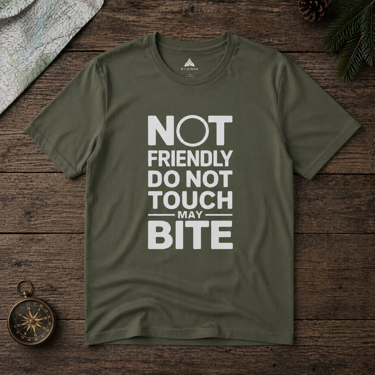 Green t-shirt with text 'Not friendly do not touch may bite' on a wooden surface.