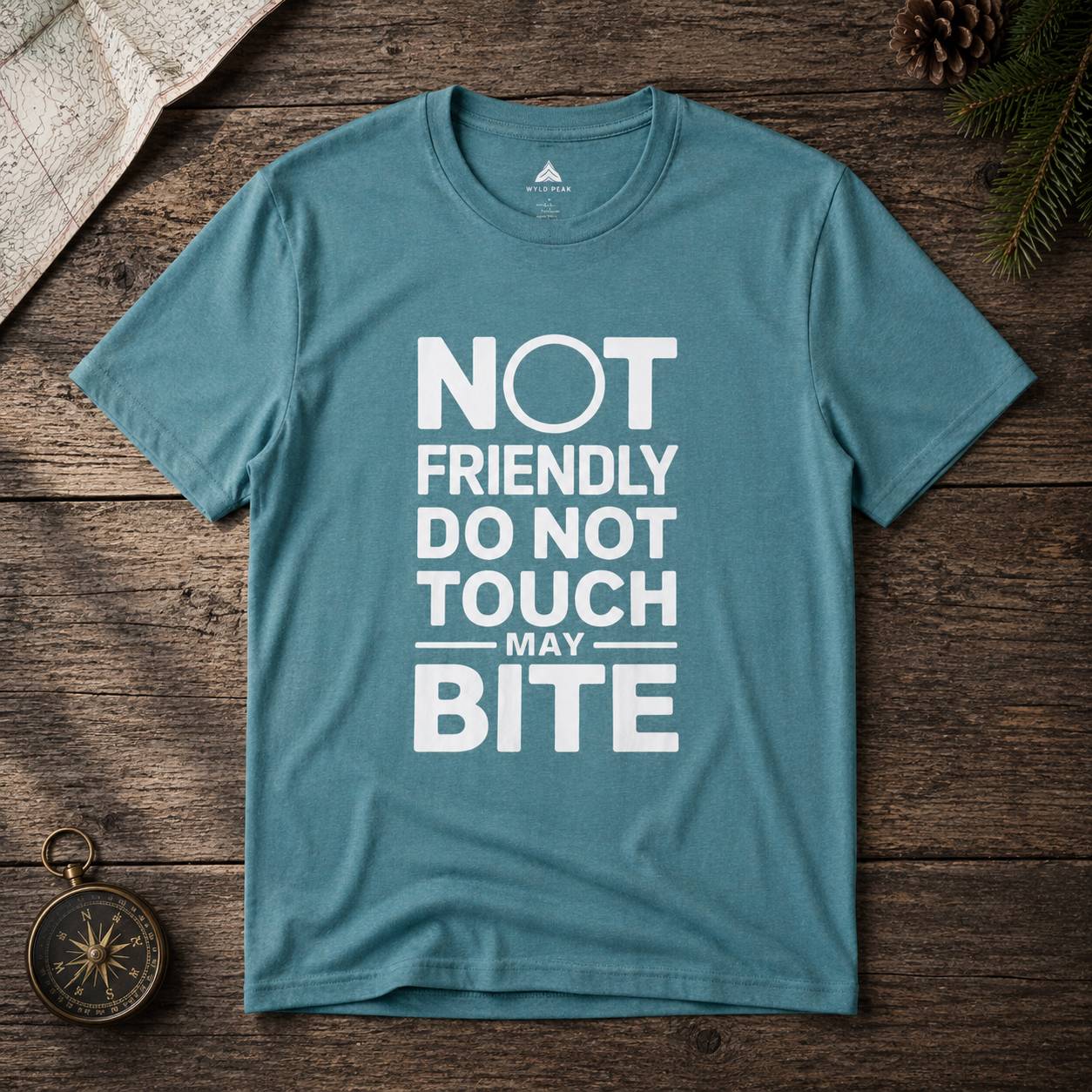 Blue t-shirt with white text 'NOT FRIENDLY DO NOT TOUCH MAY BITE' on a wooden surface.