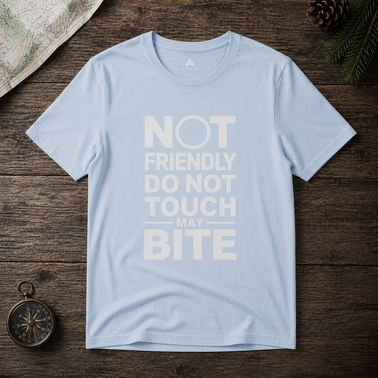 Light blue t-shirt with text 'Not friendly do not touch may bite' on a wooden surface.