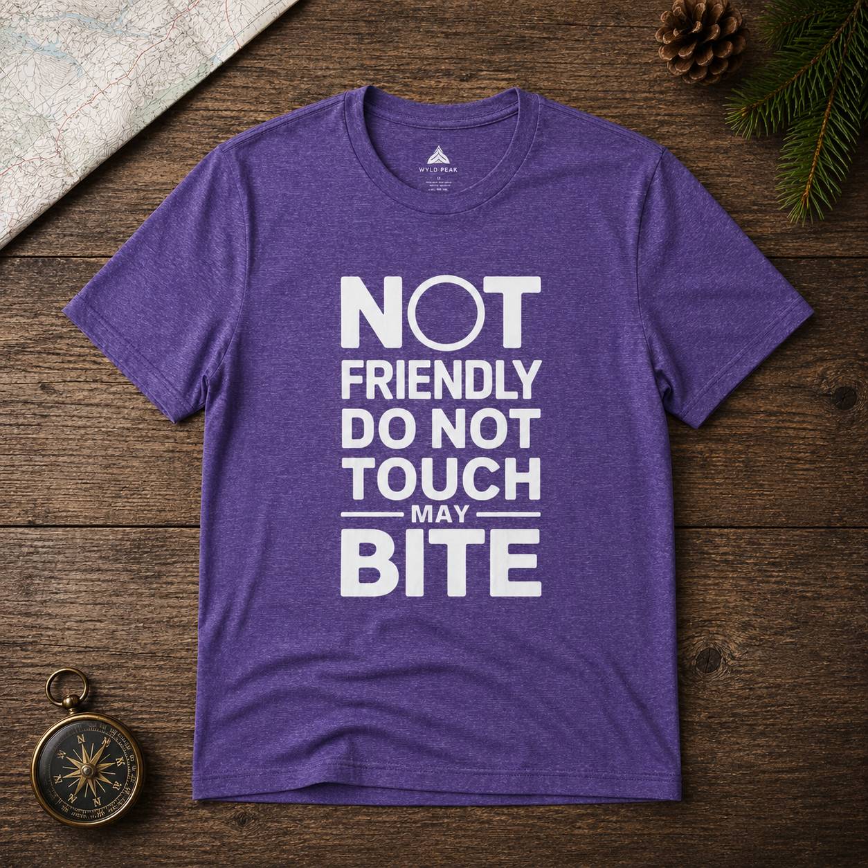 Purple t-shirt with white text 'Not friendly do not touch may bite' on a wooden surface.