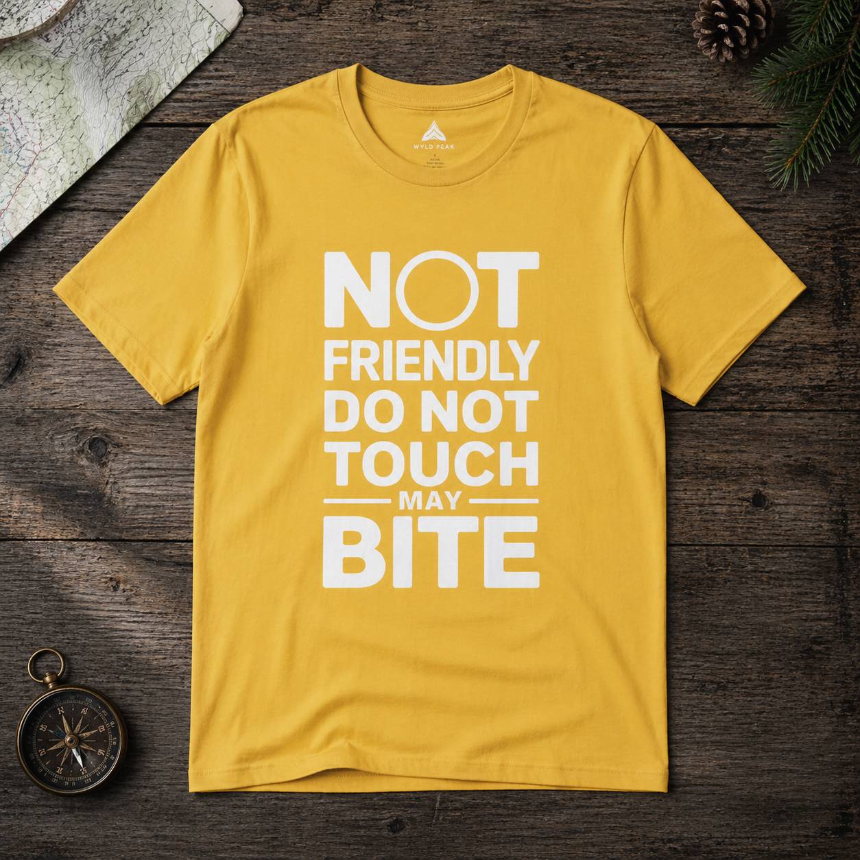 Yellow t-shirt with text 'Not friendly do not touch may bite' on a wooden surface.