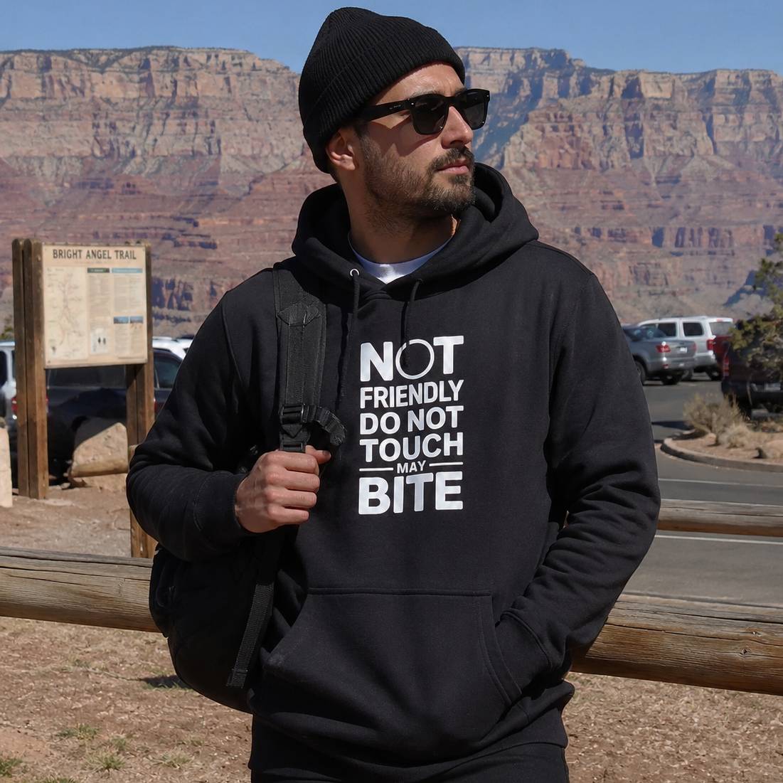 Man wearing a black hoodie with text in front of a desert landscape