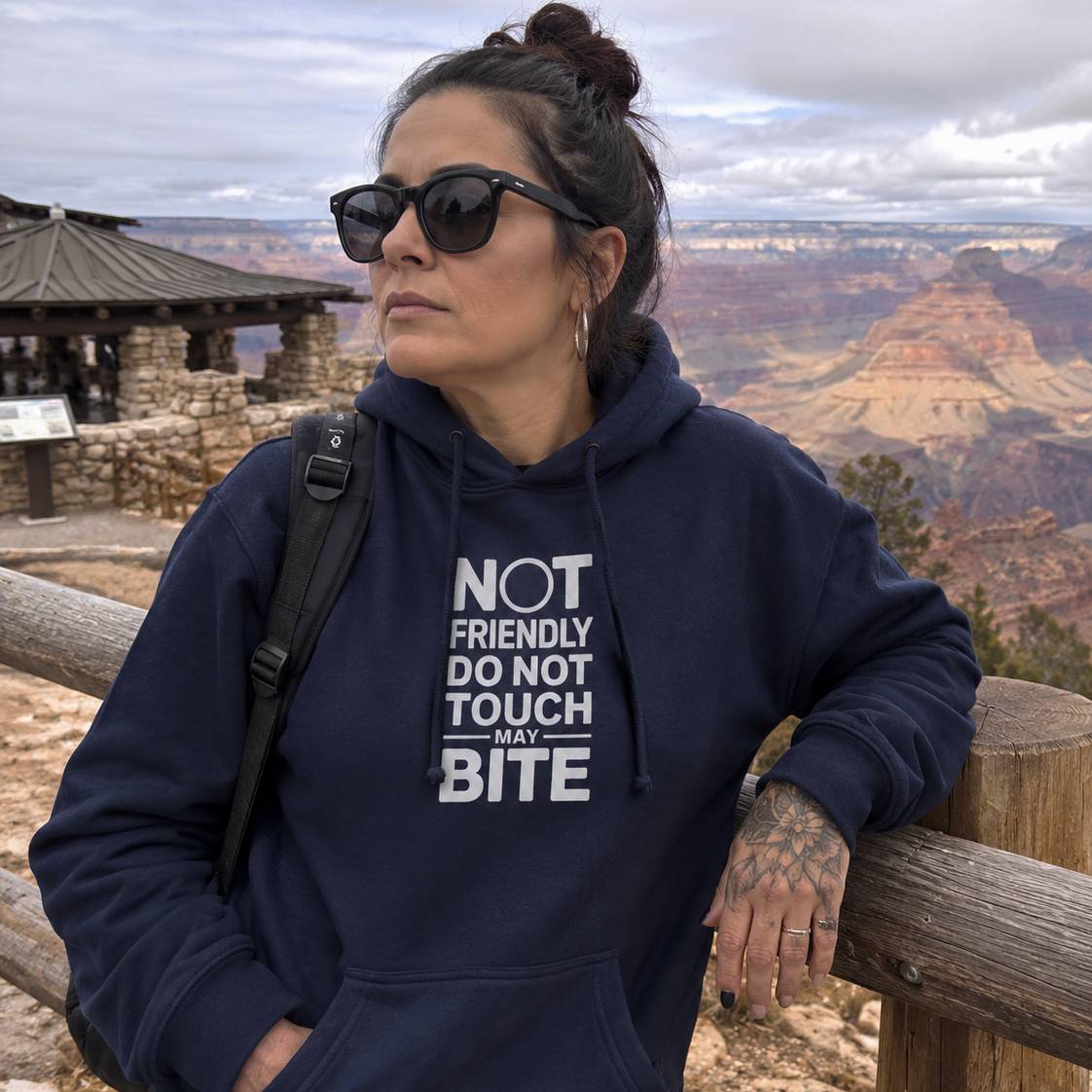 Person wearing a navy hoodie with text at a scenic location