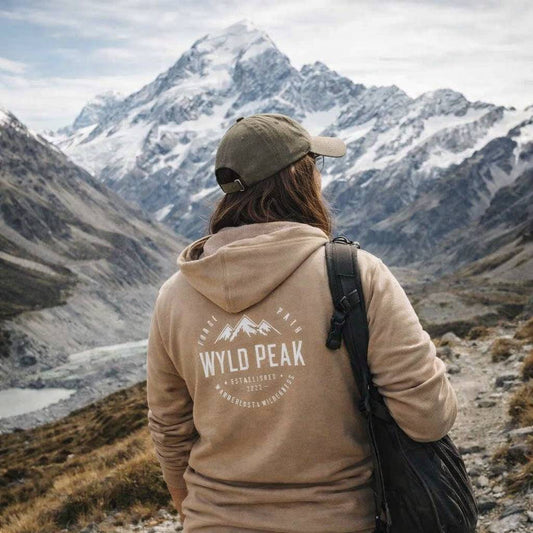 Person wearing a 'Wyld Peak' hoodie in a mountainous landscape