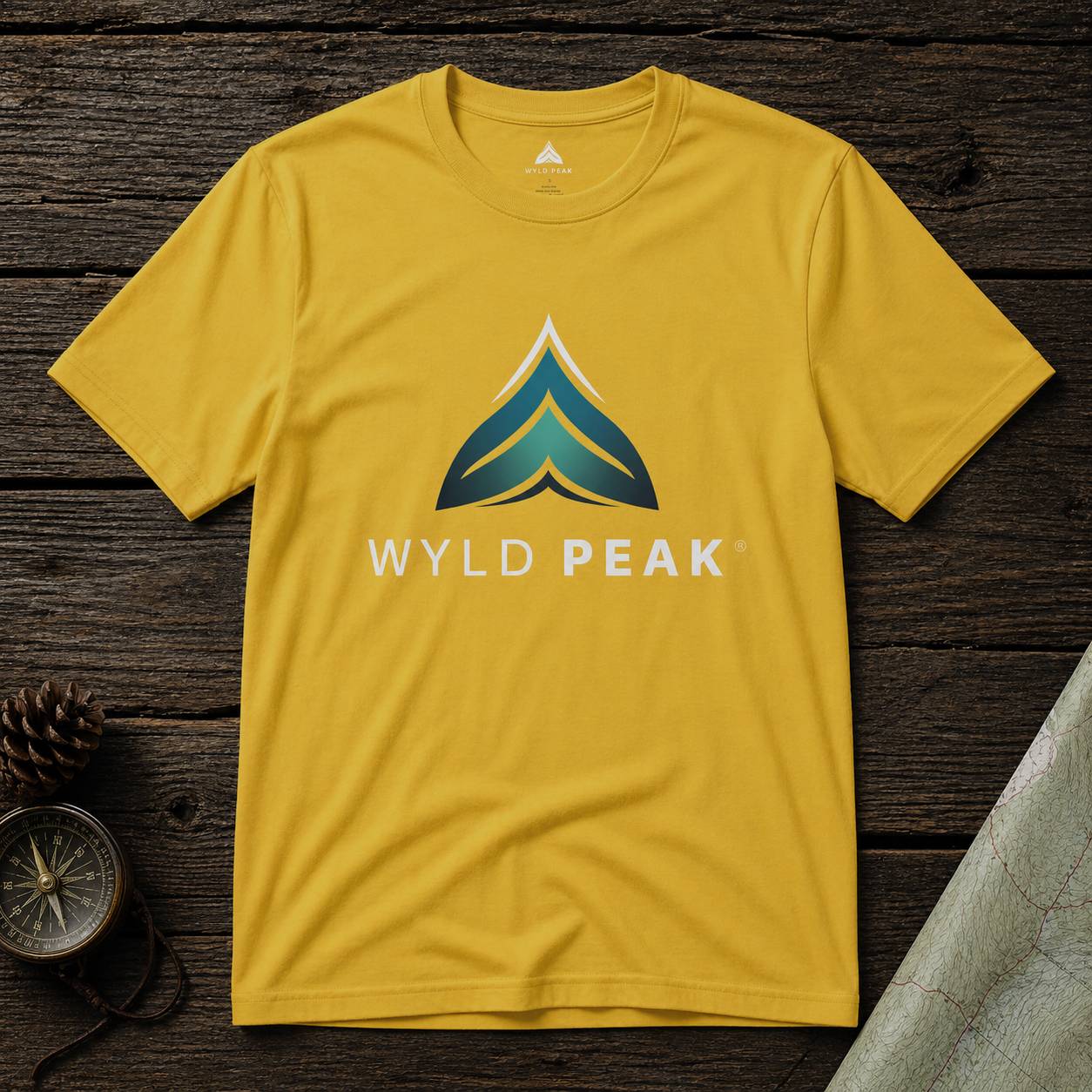 Yellow t-shirt with 'WYLD PEAK' logo on a wooden surface